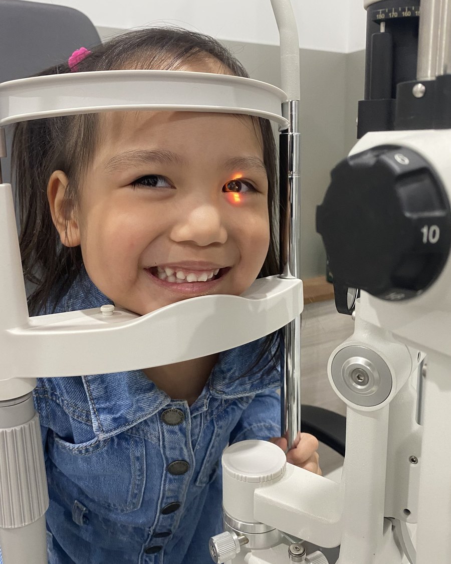 A smiling girl at the slit lamp during her eye test