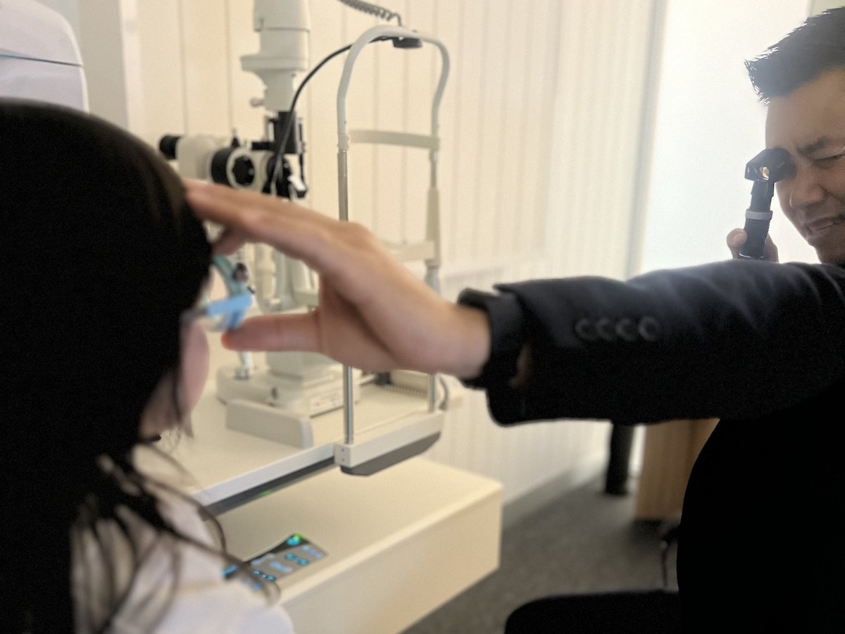 Dr Lam gently steadying a child's head while checking her eyes